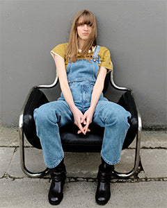 Femme assise portant une salopette en denim | Atelier Tuffery